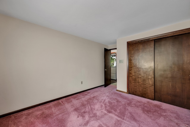 unfurnished bedroom with light colored carpet, baseboards, and a closet