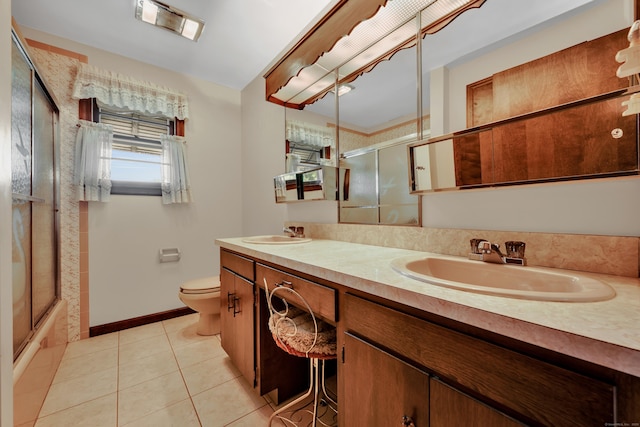 full bathroom with tile patterned floors, toilet, double vanity, enclosed tub / shower combo, and baseboards