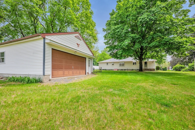 view of grassy yard featuring a detached garage and an outbuilding