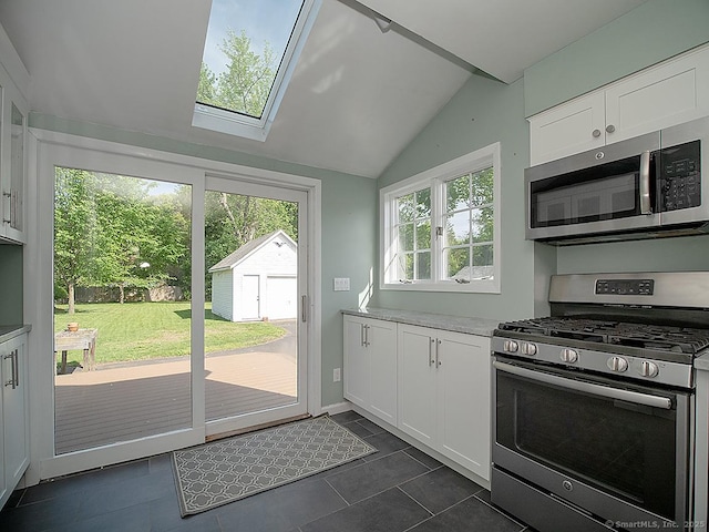 283 Quinnipiac Ave, North Haven, CT 06473 - kitchen with stainless steel appliances, vaulted ceiling, white cabinets, a skylight, and dark tile patterned flooring
