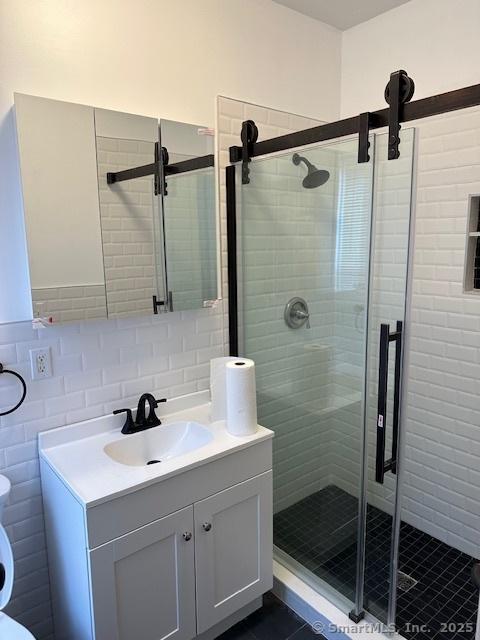 36 Bellevue Ave, Bristol, CT 06010 - bathroom with a shower stall, vanity, toilet, tile walls, and tile patterned flooring