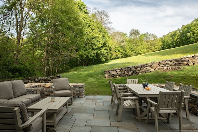 view of patio / terrace featuring an outdoor hangout area, outdoor dining area, and a wooded view