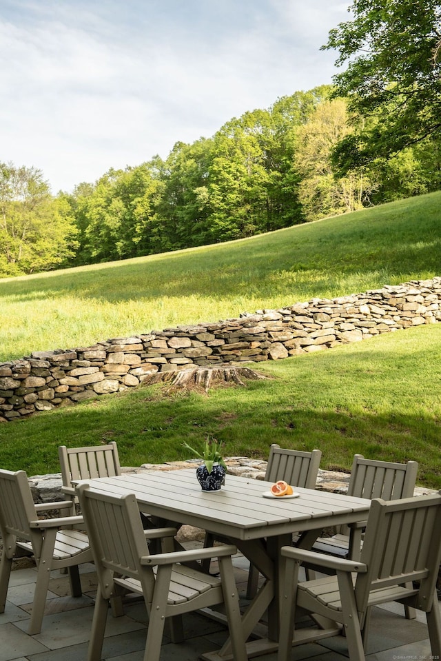 view of patio / terrace with outdoor dining area and a wooded view