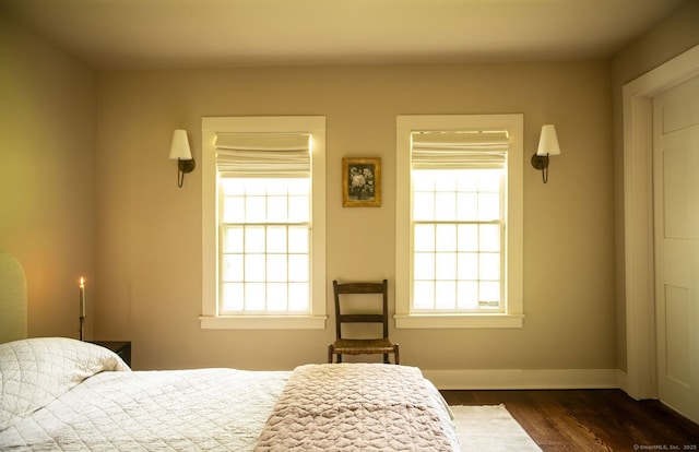 bedroom with dark wood-style flooring, multiple windows, and baseboards