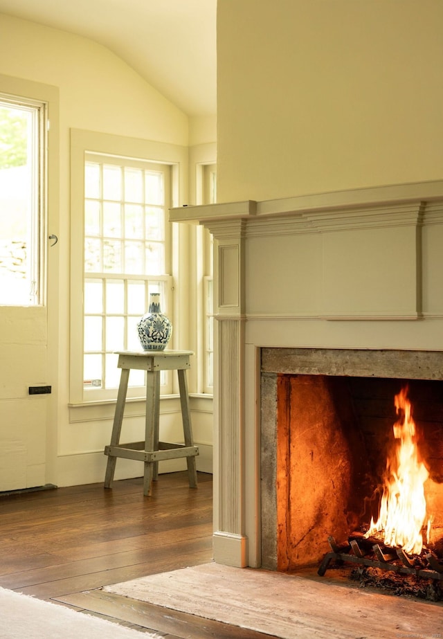 detailed view of wood finished floors and a lit fireplace
