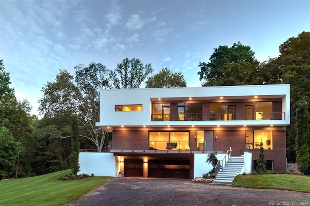 contemporary house featuring stairway, an attached garage, driveway, and a front yard