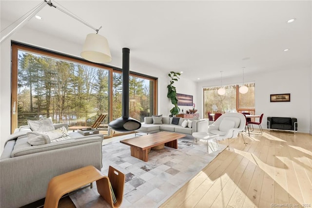 living area with wood-type flooring, recessed lighting, and a wood stove