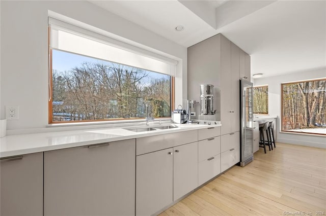 kitchen featuring a sink, stainless steel fridge, light countertops, and light wood-style floors