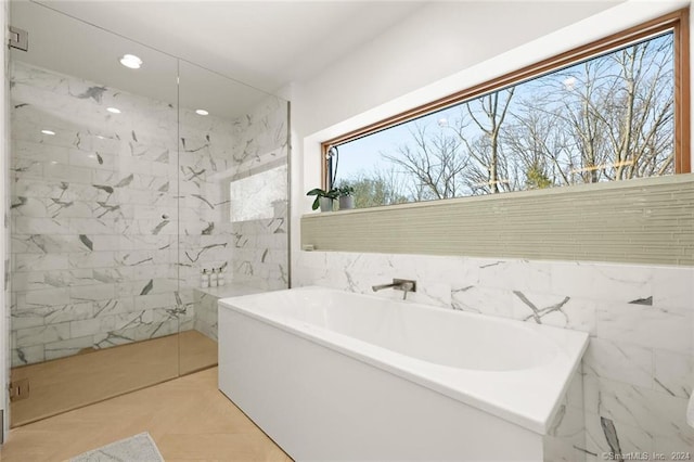 bathroom with a soaking tub, recessed lighting, a marble finish shower, and tile walls
