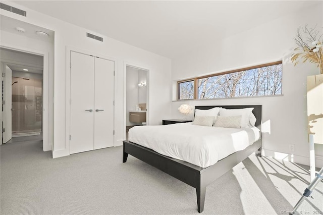 carpeted bedroom with ensuite bathroom, a closet, and baseboards