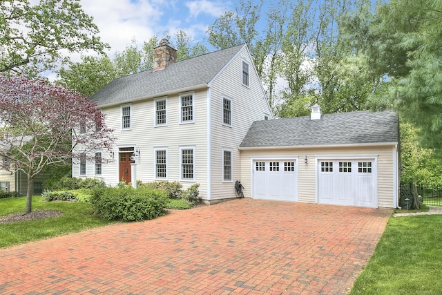 127 College Park Dr, Fairfield, CT 06824 - colonial-style house featuring a chimney, decorative driveway, an attached garage, fence, and roof with shingles