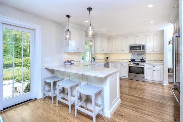 127 College Park Dr, Fairfield, CT 06824 - kitchen with appliances with stainless steel finishes, white cabinets, light countertops, a peninsula, and recessed lighting