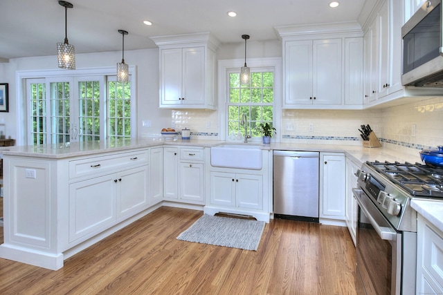 127 College Park Dr, Fairfield, CT 06824 - kitchen with appliances with stainless steel finishes, a peninsula, light wood-style floors, a sink, and recessed lighting