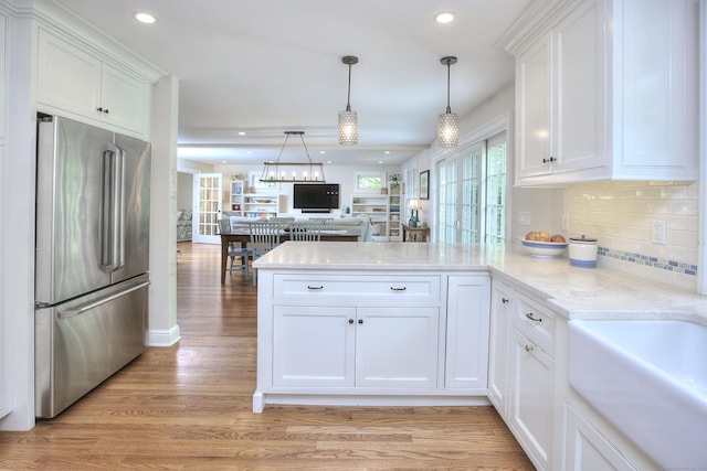 127 College Park Dr, Fairfield, CT 06824 - kitchen featuring freestanding refrigerator, a peninsula, white cabinets, light wood-type flooring, and decorative backsplash
