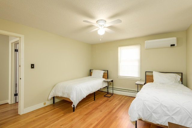 15 Haywardville Rd, East Haddam, CT 06423 - bedroom with an AC wall unit, light wood-style flooring, a baseboard radiator, baseboards, and a ceiling fan