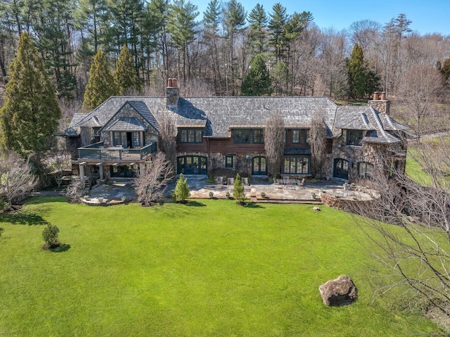 118 John St, Greenwich, CT 06831 - rear view of house featuring a chimney, a yard, a patio, stone siding, and a balcony