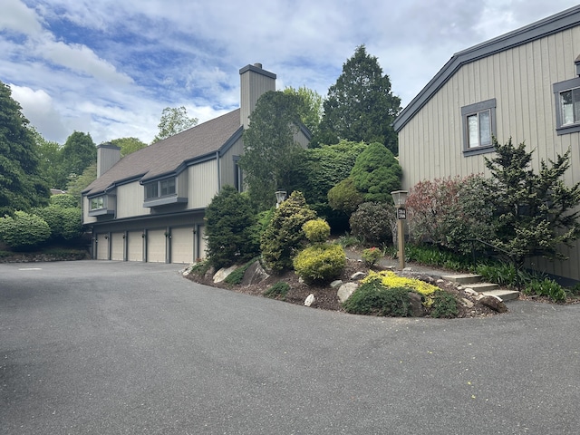 787 Heritage Vlg Unit A, Southbury, CT 06488 - view of side of home featuring a chimney, asphalt driveway, and a garage