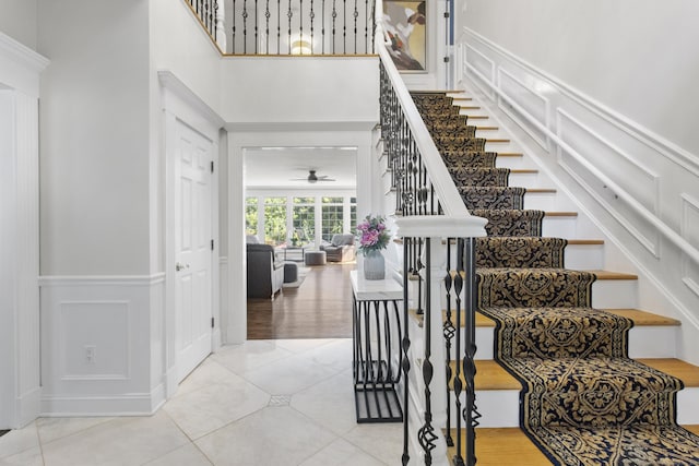 122 Mirey Dam Rd, Middlebury, CT 06762 - stairway featuring ceiling fan, a wainscoted wall, tile patterned flooring, a towering ceiling, and a decorative wall