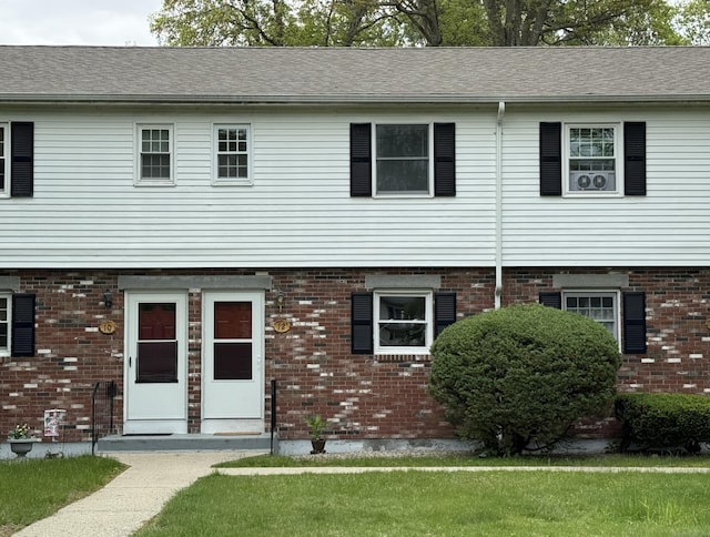 view of front of home featuring brick siding, a shingled roof, and a front lawn