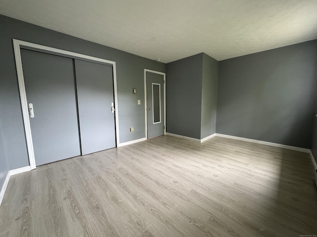 unfurnished bedroom featuring wood finished floors, baseboards, and a closet