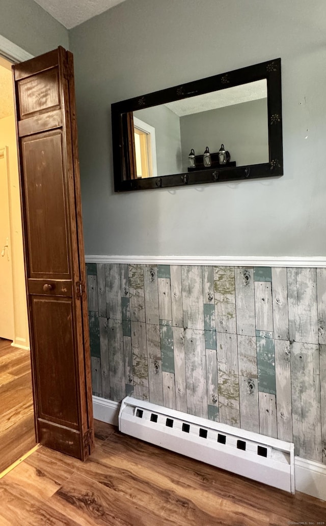 detailed view of wood finished floors, wood walls, a wainscoted wall, and baseboard heating