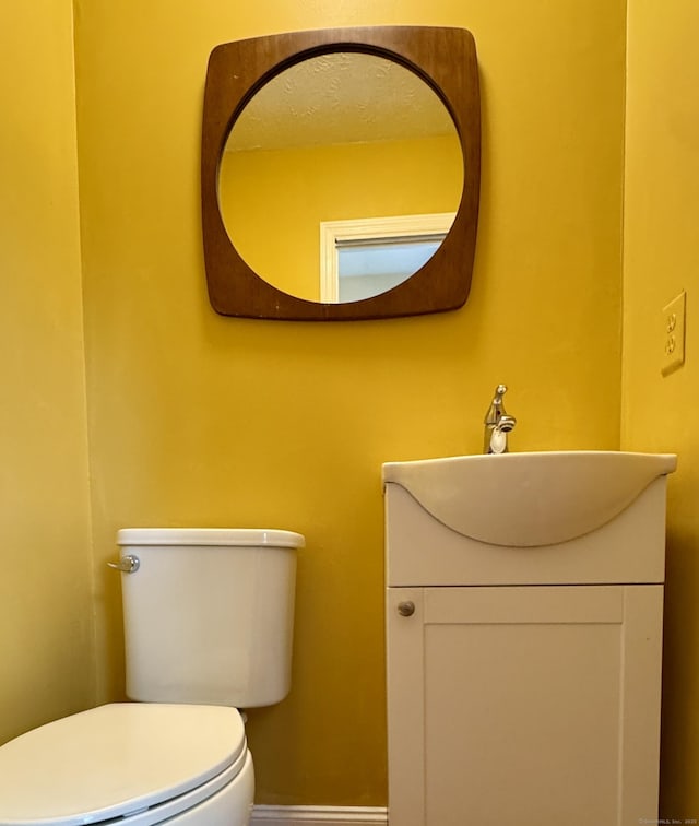 half bath with toilet, vanity, and baseboards