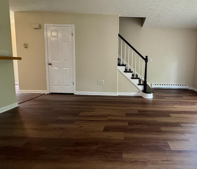 foyer entrance with a baseboard radiator, wood finished floors, baseboards, stairs, and a textured ceiling