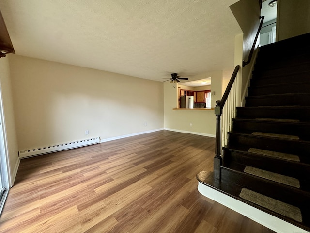 stairway with baseboard heating, a ceiling fan, wood finished floors, a textured ceiling, and baseboards