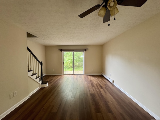 empty room featuring a baseboard heating unit, a textured ceiling, dark wood-style flooring, stairway, and ceiling fan