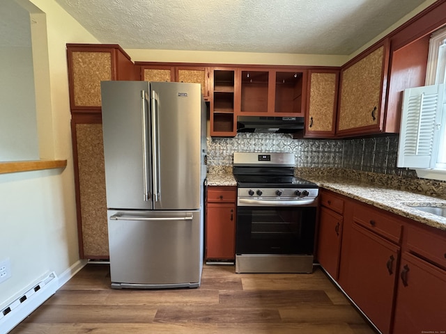 kitchen featuring appliances with stainless steel finishes, baseboard heating, under cabinet range hood, wood finished floors, and a textured ceiling