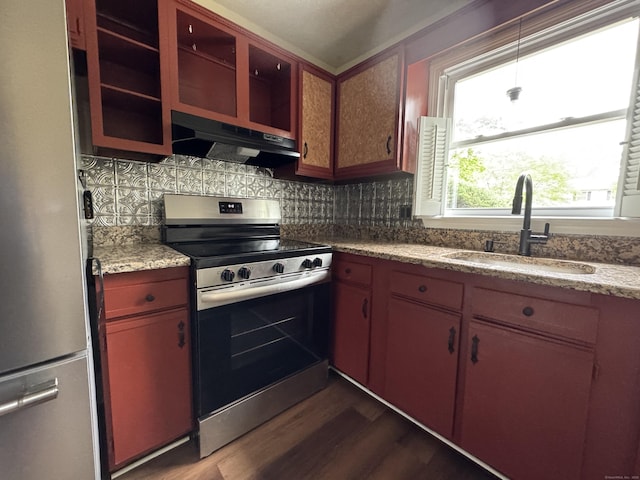kitchen featuring stainless steel appliances, under cabinet range hood, a sink, dark wood-style floors, and tasteful backsplash