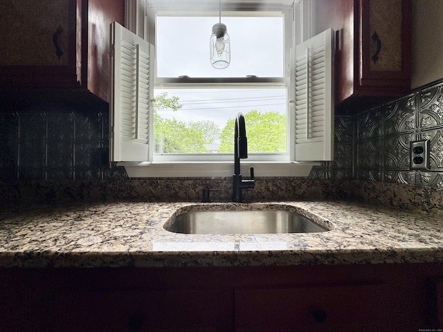 kitchen featuring a sink, tasteful backsplash, and light stone counters