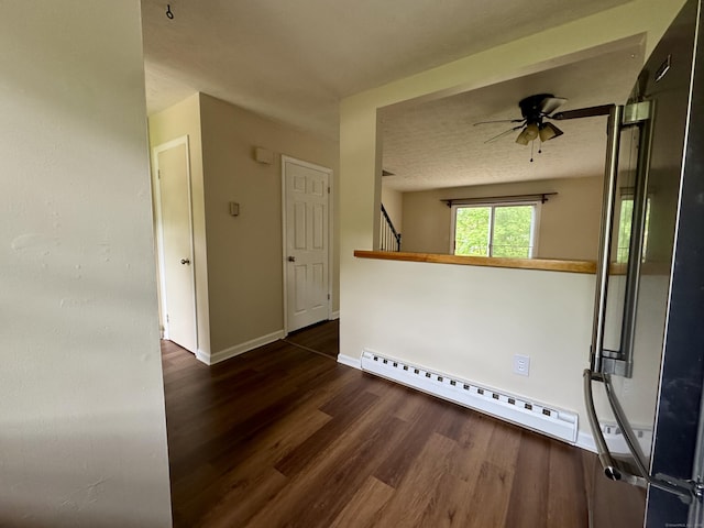 unfurnished room with baseboard heating, wood finished floors, baseboards, and ceiling fan