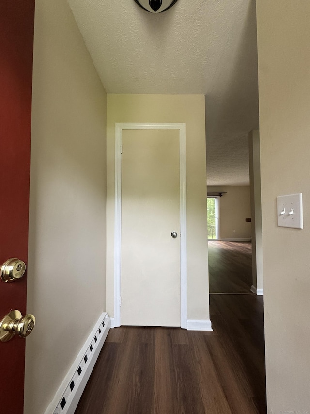 corridor with baseboard heating, dark wood finished floors, baseboards, and a textured ceiling