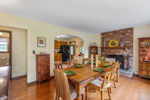 19 Edgewood St, Cromwell, CT 06416 - dining room featuring arched walkways, light wood-type flooring, a fireplace, baseboard heating, and baseboards