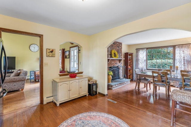 19 Edgewood St, Cromwell, CT 06416 - dining area with a baseboard radiator, a fireplace, hardwood / wood-style flooring, and arched walkways