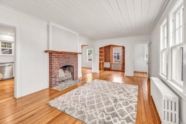 61 Reed St, Stratford, CT 06614 - living room featuring radiator, ornamental molding, a brick fireplace, wood finished floors, and arched walkways