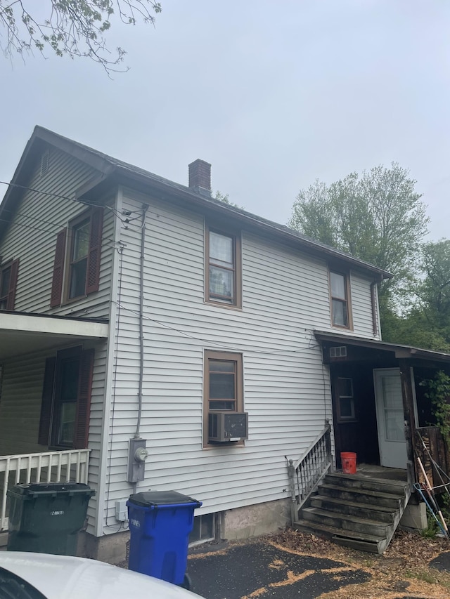 view of property exterior featuring a chimney and cooling unit