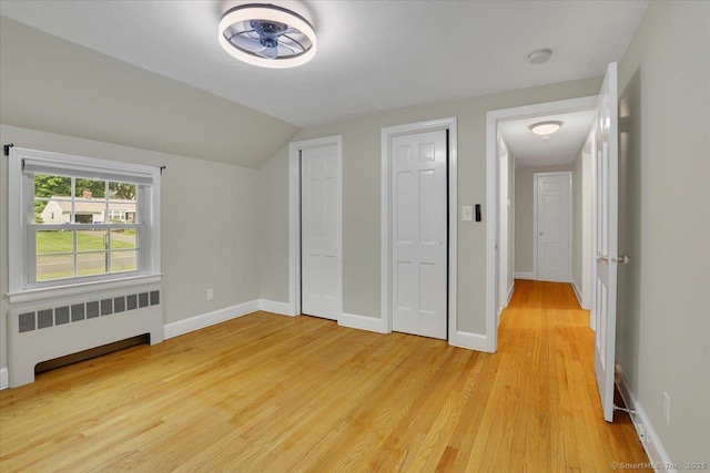 184 Goodale Dr, Newington, CT 06111 - unfurnished bedroom with radiator, light wood-style floors, lofted ceiling, baseboards, and two closets