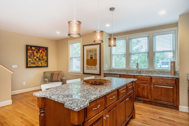 645 Prospect Ave Unit 9, West Hartford, CT 06105 - kitchen with a sink, light stone counters, light wood-style floors, a kitchen island, and baseboards