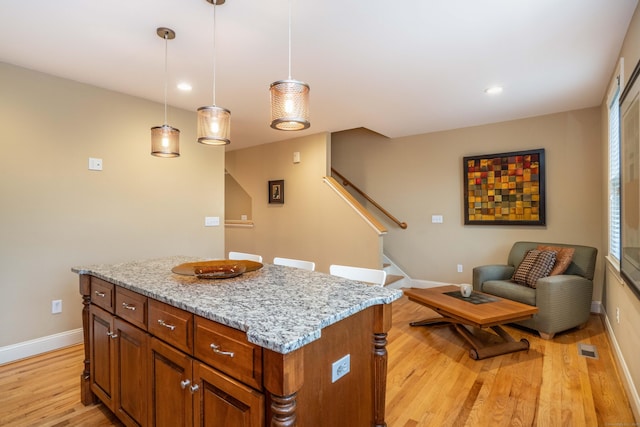 645 Prospect Ave Unit 9, West Hartford, CT 06105 - kitchen featuring light wood-style flooring, baseboards, a kitchen island, light stone countertops, and hanging light fixtures