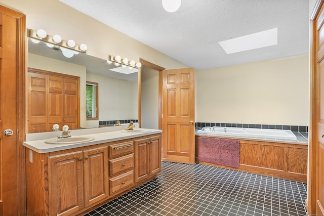 223 Sterling Rd, Trumbull, CT 06611 - full bathroom with a skylight, tile patterned floors, double vanity, a garden tub, and a textured ceiling