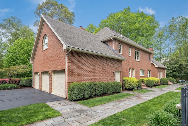 188 Bartlett Dr, Madison, CT 06443 - view of property exterior with a chimney, asphalt driveway, a garage, roof with shingles, and brick siding