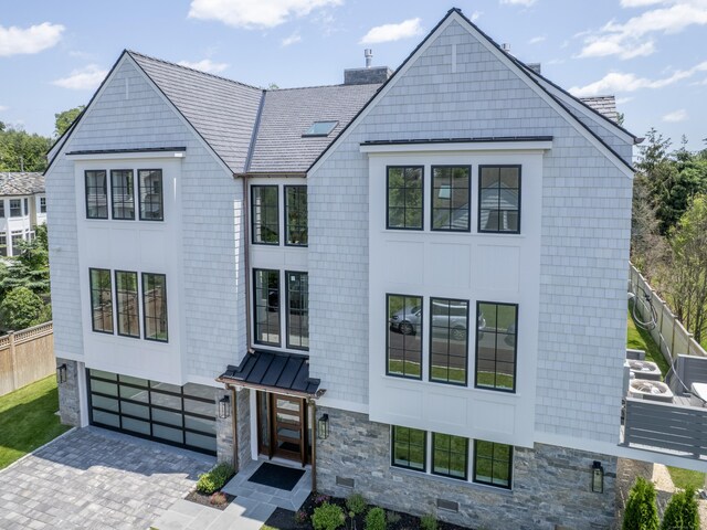 22 Apple Tree Trl, Westport, CT 06880 - view of front facade featuring stone siding, a chimney, driveway, a standing seam roof, and a garage
