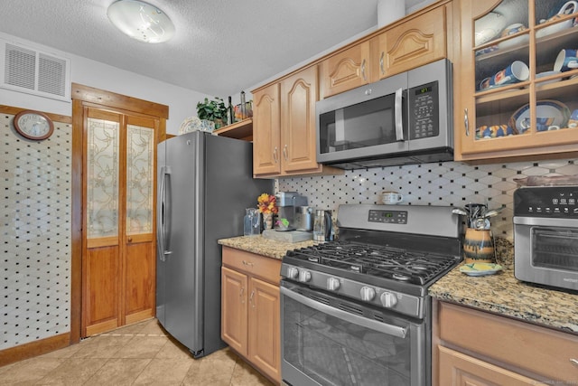 41 Farm Dr Unit 41, Farmington, CT 06032 - kitchen with stainless steel appliances, light stone countertops, glass insert cabinets, decorative backsplash, and a textured ceiling