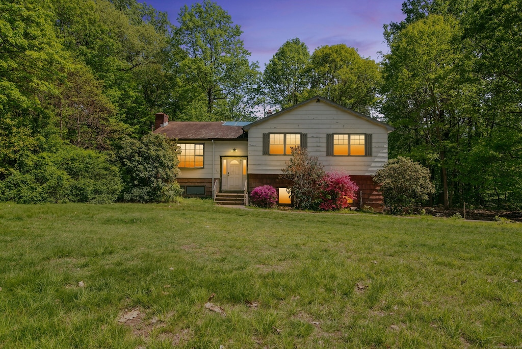 tri-level home with a chimney and a lawn