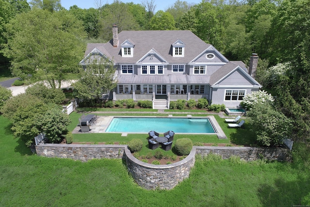 67 Peaceable St, Ridgefield, CT 06877 - back of property with a chimney, a lawn, an outdoor pool, and a wooded view