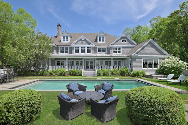 67 Peaceable St, Ridgefield, CT 06877 - rear view of house with an outdoor pool, a chimney, metal roof, a standing seam roof, and a lawn