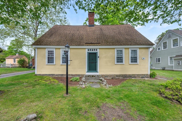 cape cod house featuring a chimney and a front yard