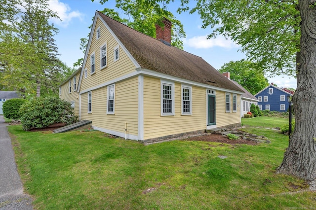 view of home's exterior featuring a chimney and a lawn